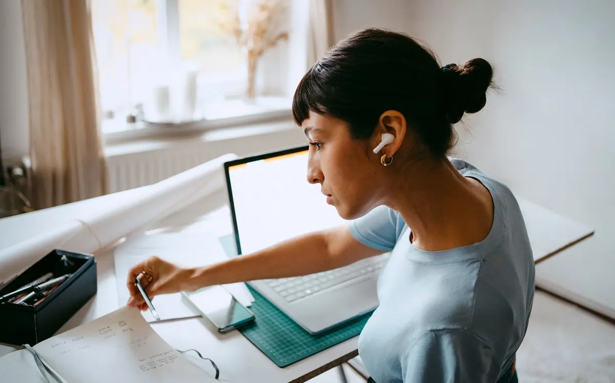 Person wearing wireless earbuds works at a laptop